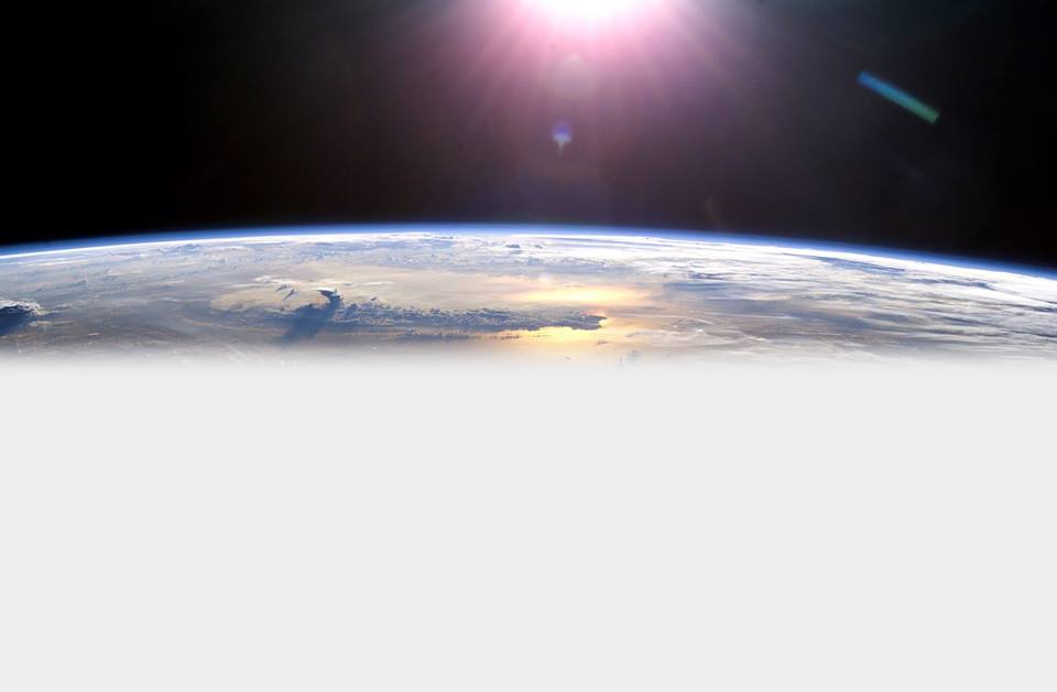 Aerial view of earth from outer space with sun shining down from above.