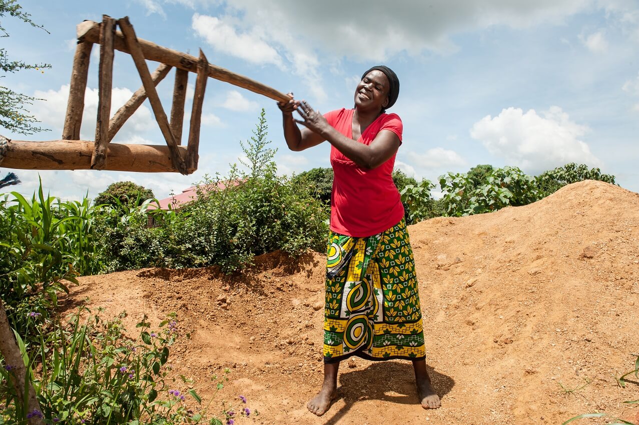 A smiling African woman holds onto a wooden fixture.
