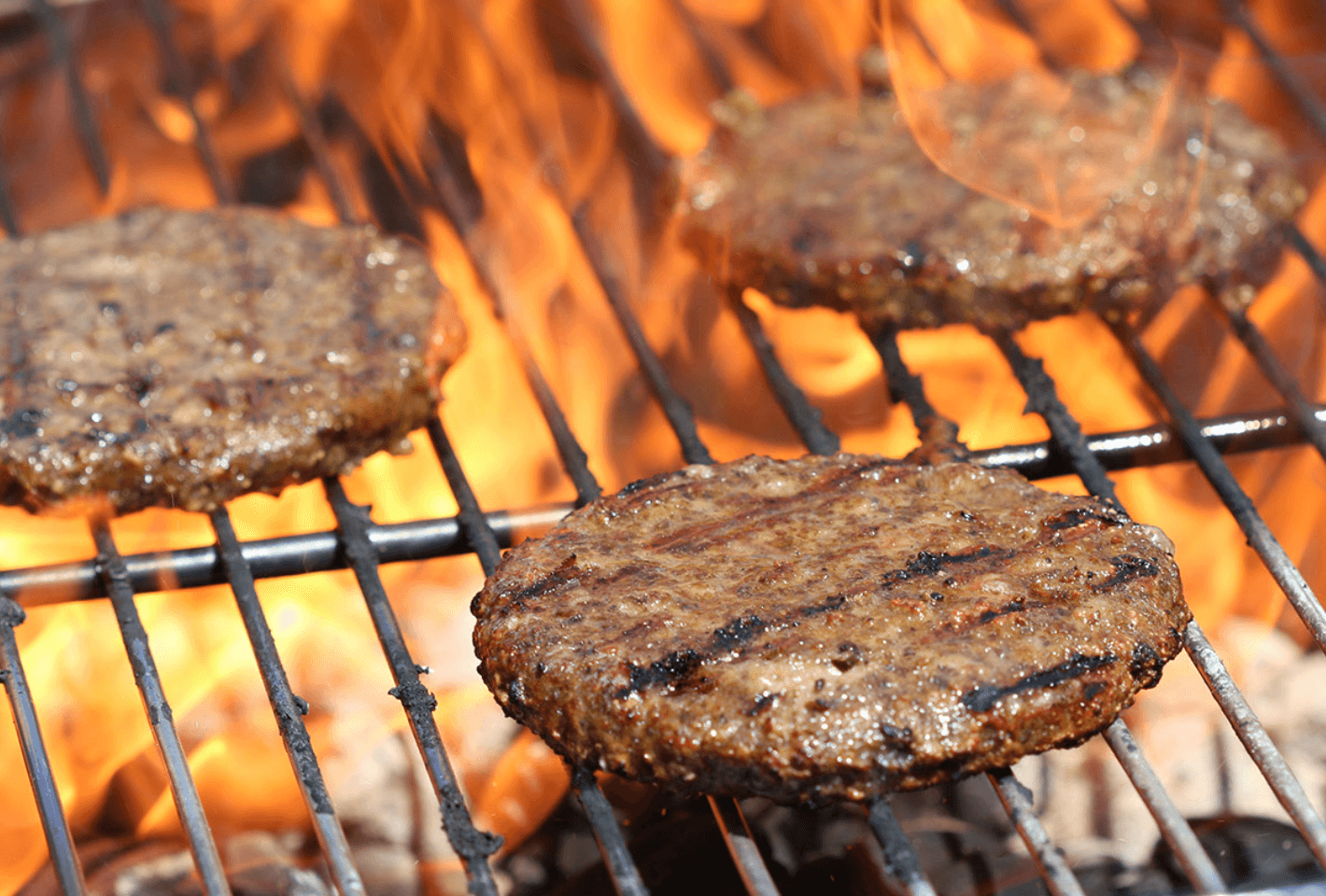 Three plant-based burgers on a grill.