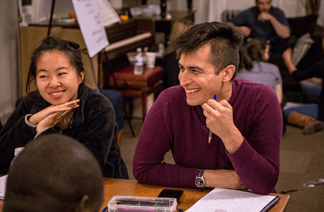 Two CFAR workshop participants attentively listening to another participant and smiling.