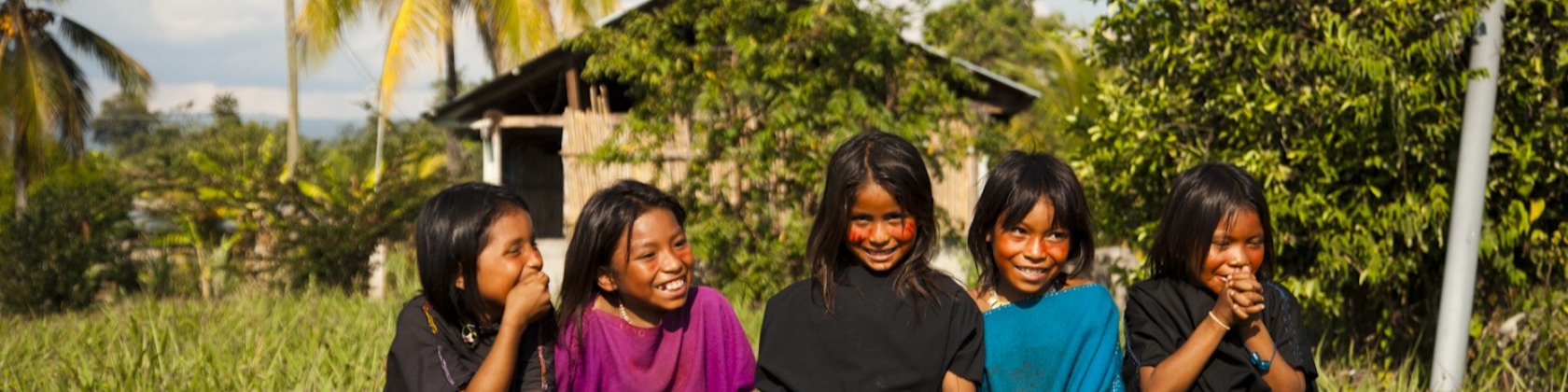 Five indigenous children pose for a photo in front of their rural home
